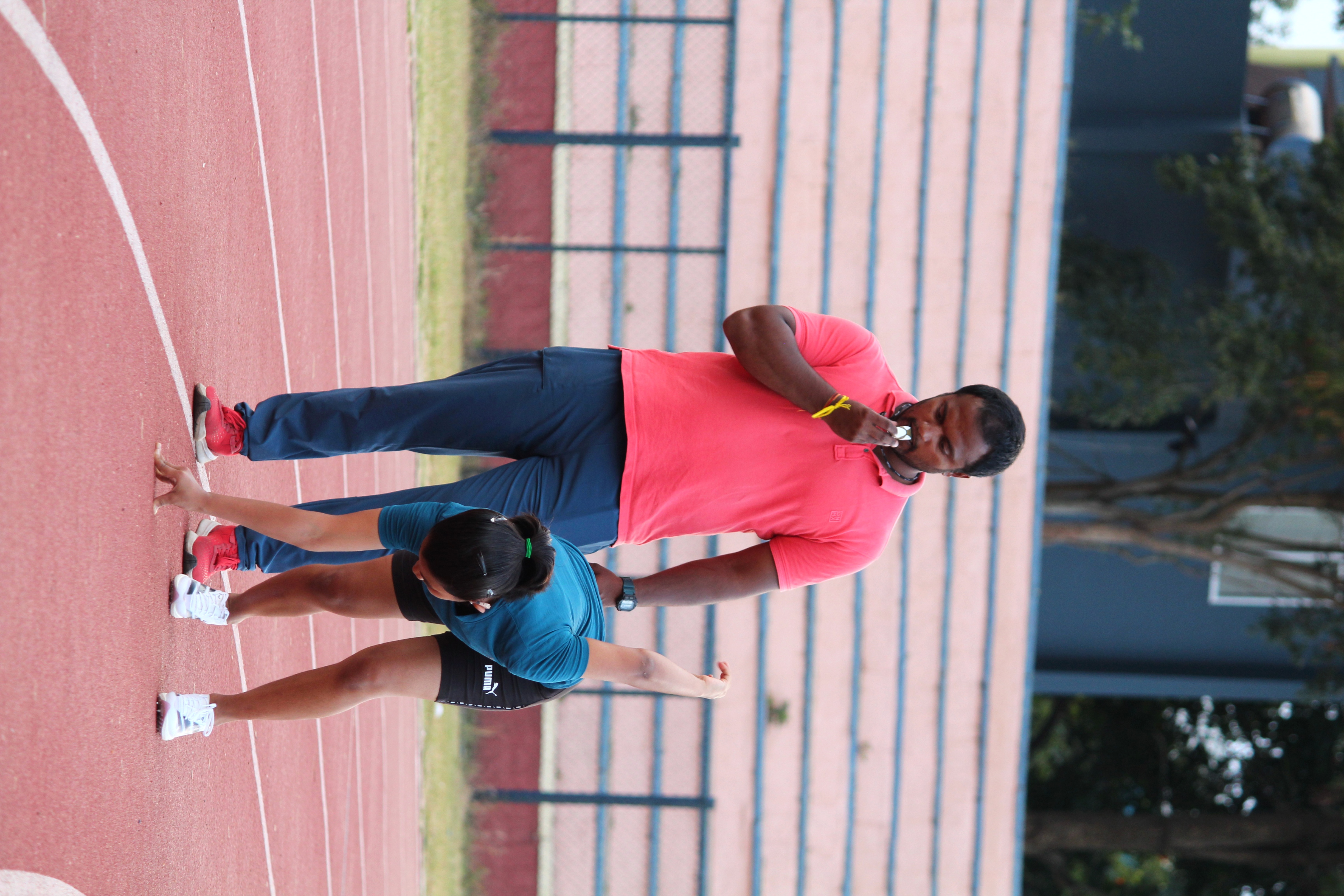 Coach Radesh guiding Rishitha through a movement drill on the track